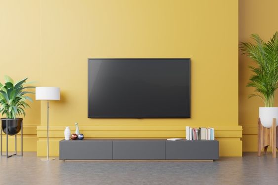 Parede amarela com rack cinza e tv fixa na parede
